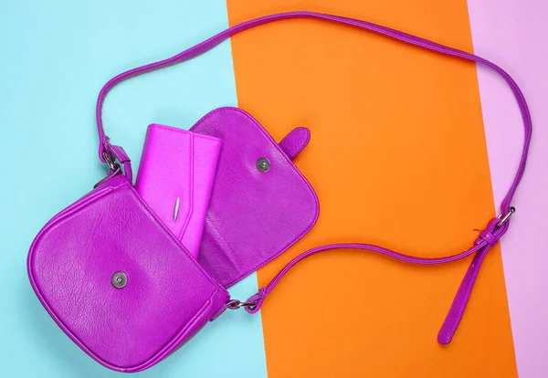 Purple pink leather bag with purse on pastel colored background. Top view