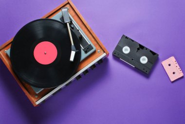 Mor arkaplanda geriye dönük ögeler. Vinil çalar, video, ses kaseti, oyun alanı. Popüler kültür, 80 'ler. Üst görünüm