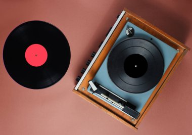 Retro 70 'lerin vinil plakçısının kahverengi arka planda plağı var. Üst görünüm, minimalizm