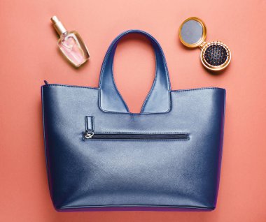 Kadın aksesuarları. Deri çanta, parfüm şişesi, kırmızı kağıtta tarak aynası. Üst görünüm