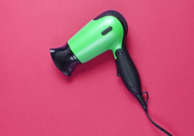 Kırmızı arka planda saç kurutma makinesi. Üst görünüm