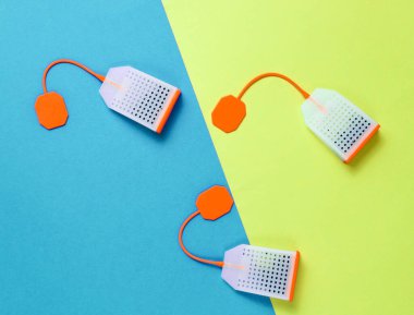 Renkli arka planda üç silikon çay poşeti. Üst görünüm, minimalizm