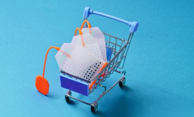 Mavi arka planda oyuncak alışveriş arabasında çay poşetleri. Kavramsal fotoğraf.