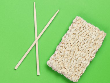 Çiğ erişte ve yeşil arka planda Çin çubukları, minimalizm.