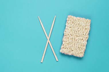 Çiğ erişte ve Çin yemek çubukları mavi arka planda, minimalizm