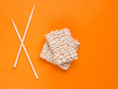 Çiğ erişte ve portakal arka planda Çin yemek çubukları, minimalizm. Üst görünüm