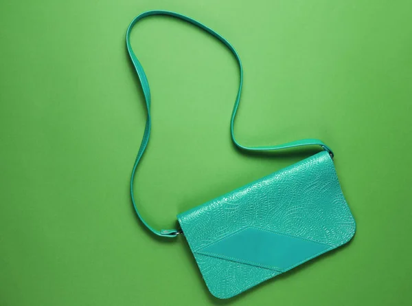 Retro style blue leather bag on green background. Top view