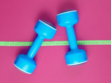 Kilo verme kavramı. Mavi plastik halterler, mor arka planda cetvel. Spor, spor. Üst Manzara. Düz yatıyordu