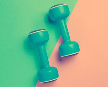 Pastel arka planda iki mavi plastik dambıl, spor, spor konsepti. Üst Manzara. Düz yatıyordu. Minimalizm