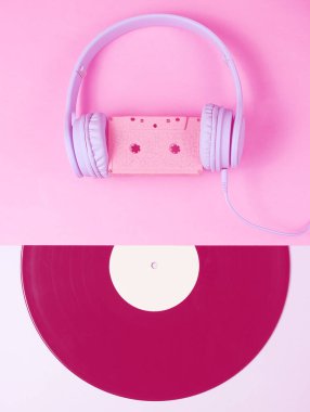 Minimalizm. Retro tarzı. Ses kaseti olan kulaklık, pembe gri arka planda lp kaydı. Yaratıcı Düzlük. Duotone etkisi