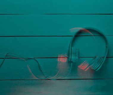 Kulaklıklar ahşap arka planda. Retro dalga, neon ışık, morötesi. Üst görüş, minimalizm. Hafif duoton arıza efekti