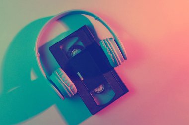 Kulaklıklı video kaset. Retro dalga, kırmızı mavi ışık, ultraviyole. Üst görünüm, minimalizm
