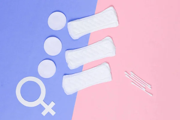 Products for feminine hygiene, self-care and health, female gender symbol on pastel background. Ear sticks, pads. Top view