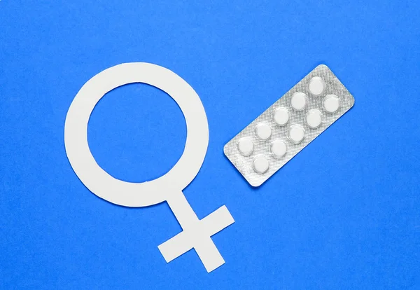 Women Health. Female gender symbol, pills on blue background.