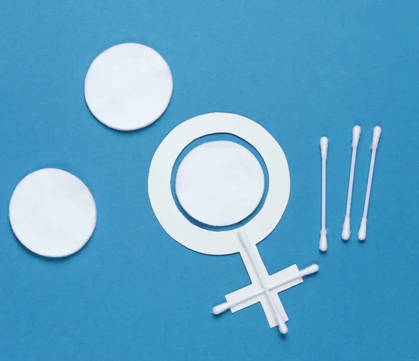 Products for feminine hygiene, self-care and health, female gender symbol on blue background. Ear sticks, pads. Top view