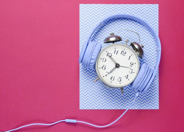 时间听音乐的概念 复古报警器 带带着带粉色蓝色创意背景的有线耳机 顶部视图 — 图库照片