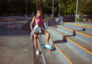 Retro kameralı ve kaykaylı kadın kaykaycı.