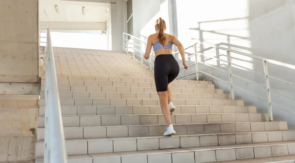 Young slim fit woman runs up the stairs. Urban workout