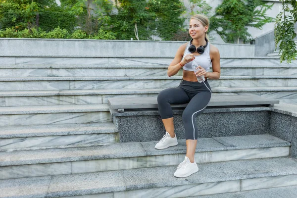 Vrolijke Sportvrouw Sportkleding Rust Tijdens Het Zitten Een Bank Drinkt — Stockfoto