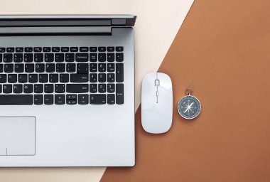 Laptop, bilgisayar, pusula ve bej rengi kahverengi arka plan. Çevrimiçi iş veya seyahat. Üst görünüm