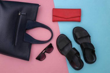 Pembe pastel arka planda yassı kadın aksesuarları. Sandaletler, çanta, deri cüzdan ve güneş gözlüğü. Üst görünüm