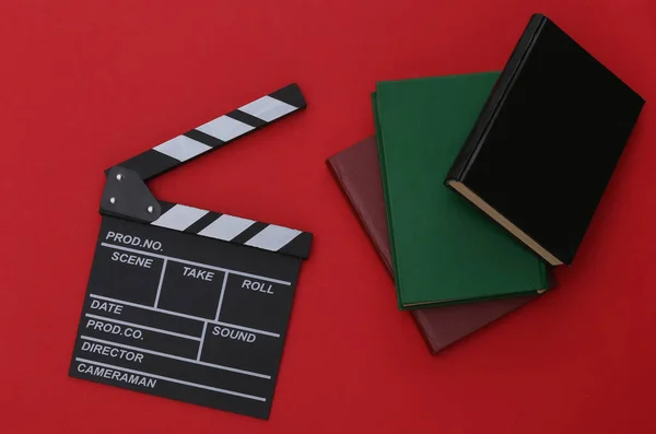 Film clapper board and books on red background. Movie by book. Cinema industry, entertainment. Top view