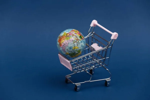 全球市场 带有经典蓝色背景的地球仪的微型购物车 — 图库照片