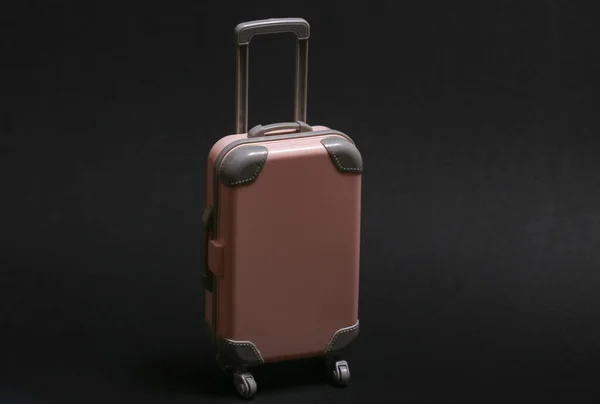 旅行や旅行のコンセプト 黒を背景にミニプラスチック旅行スーツケース ミニマルスタイル — ストック写真