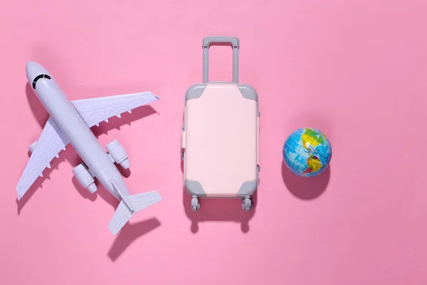Cestovní Minimalismus Mini Plastový Cestovní Kufr Glóbus Letadlo Růžovém Pozadí — Stock fotografie