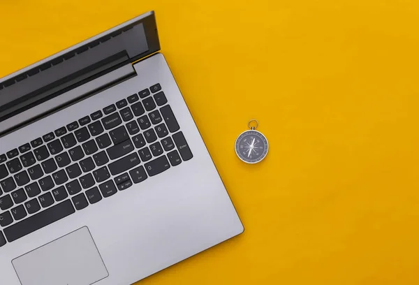 Laptop and compass on yellow background. Online business or travel. Top view