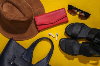 Parlak sarı arka planda kadın aksesuarlarının düz kompozisyonu vardı. Moda konsepti ya da seyahat. Üst görünüm