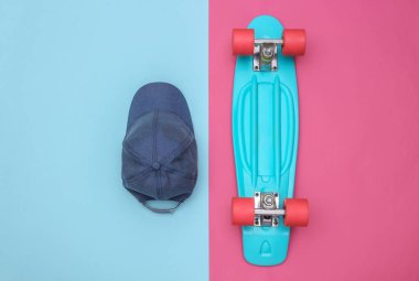 Mini kruvazör tahtasının düz kompozisyonu ve pembe mavi arka plan kapağı. Gençlik, hipster aksesuarlar. Üst görünüm