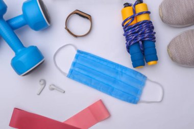 Covid-19 döneminde beden eğitimi. Spor kıyafetleri, aksesuarlar, beyaz arka planda tıbbi maske. Sağlıklı yaşam tarzı kavramı. Üst görünüm