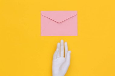 Sarı arka planda beyaz manken eli ve zarf. Üst görünüm