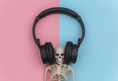 Mavi-pembe pastel arka planda büyük siyah stereo kulaklıklı iskelet. Üst görünüm