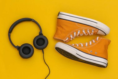 Sarı arka planda retro spor ayakkabılı Stereo kulaklıklar. Üst Manzara. Düz yatıyordu