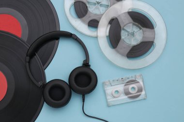 Retro vinil plaklar, ses manyetik makarası, ses kaseti ve mavi arka planda stereo kulaklık. Üst Manzara. Düz yatıyordu