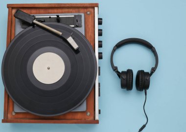 Retro vinil çalar ve mavi arka planda stereo kulaklıklar. Üst Manzara. Düz yatıyordu