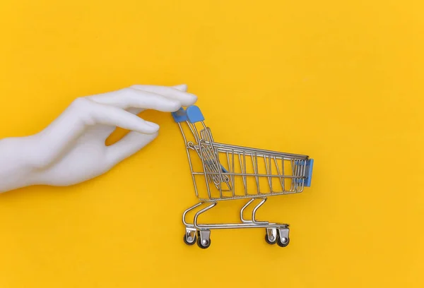 Beyaz Manken Elinde Sarı Arka Planda Mini Bir Alışveriş Arabası — Stok fotoğraf