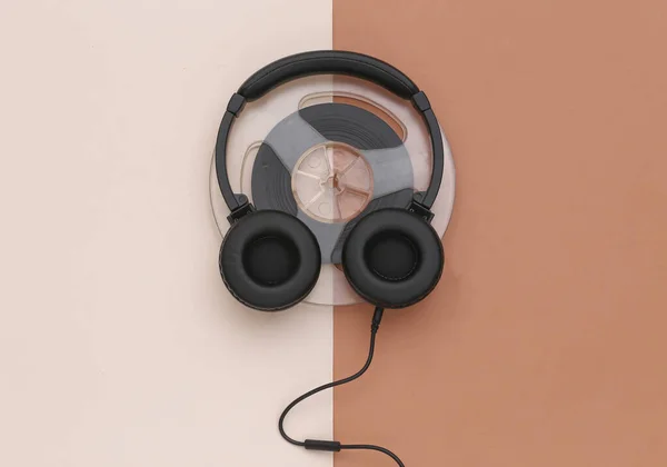 Stereo headphones and magnetic audio reel on brown beige background. Top view