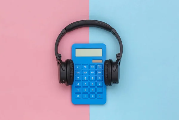 Calculator with headphones on a blue pink pastel background. Top view