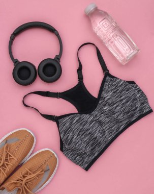 Spor sutyeni, dambıl, şişe suyu ve pembe arka planda stereo kulaklık. Spor ve spor. Üst Manzara. Düz yatıyordu