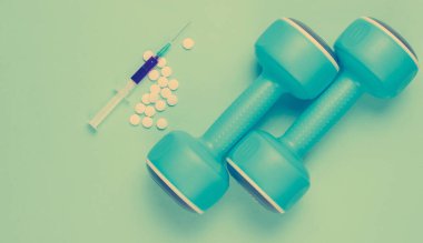 Sporda uyuşturucu. Anabolik steroid. Spor Eczanesi. Plastik halterler, şırınga, mavi arka planda haplar. Üst görünüm.