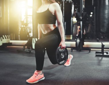 Spor salonunda antrenman bacakları. Çekici fit kadın bardan disklerle saldırıyor..