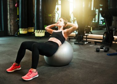 Formda olan genç bir kadın spor salonunda karın kaslarını çalıştırıyor. Kaslı spor salonunda karın kaslarını çalıştıran bir kadın.