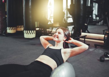 Formda olan genç bir kadın spor salonunda karın kaslarını çalıştırıyor. Kaslı spor salonunda karın kaslarını çalıştıran bir kadın.