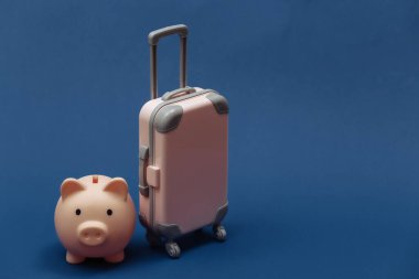 Seyahat ya da seyahat konsepti. Mini plastik seyahat çantası, klasik mavi arka planda kumbarası. Renk 2020