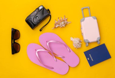 Seyahat ya da plaj oteli düzlüğü. Sarı arka planda seyahat aksesuarları. Asgari düzeyde. Üst görünüm