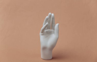 Beyaz manken, kahverengi arka planda duruyor.