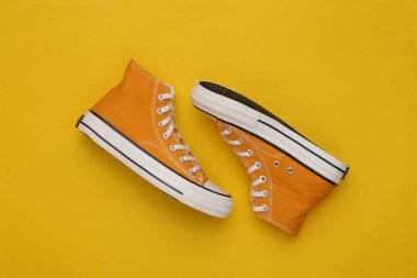 Sarı arka planda sarı yüksek topuklu ayakkabılar (jelibon). Üst Manzara. Minimalizm